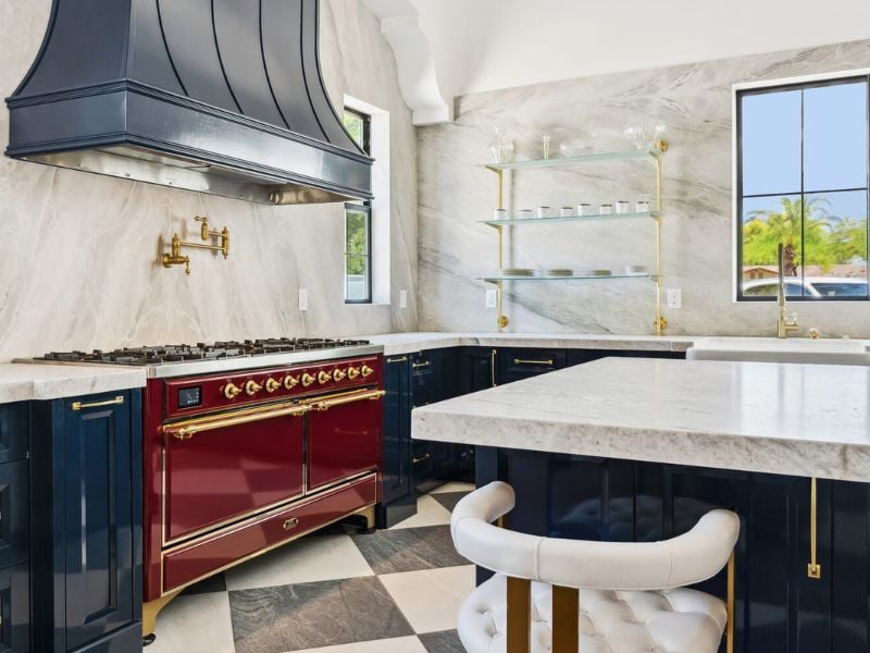 Custom kitchen design with bold red stove and gold fixtures by Trinity Homes AZ in Arizona